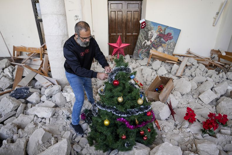 Georges Elia decora un árbol de Navidad dentro de la iglesia de San Jorge, que fue destruida por un ataque aéreo israelí, en la ciudad de Dardghaya, en el sur del Líbano, el 22 de diciembre de 2024. (AP Foto/Hassan Ammar)