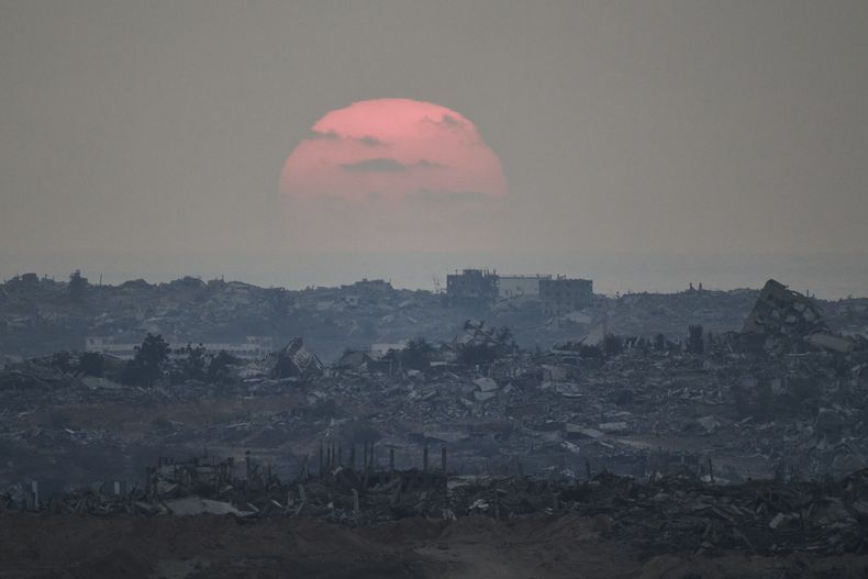 El sol se pone detrás de edificios fueron destruidos durante las operaciones terrestres y aéreas israelíes en el norte de la Franja de Gaza, visto desde el sur de Israel, el viernes 8 de agosto de 2025. (AP Foto/Leo Correa)