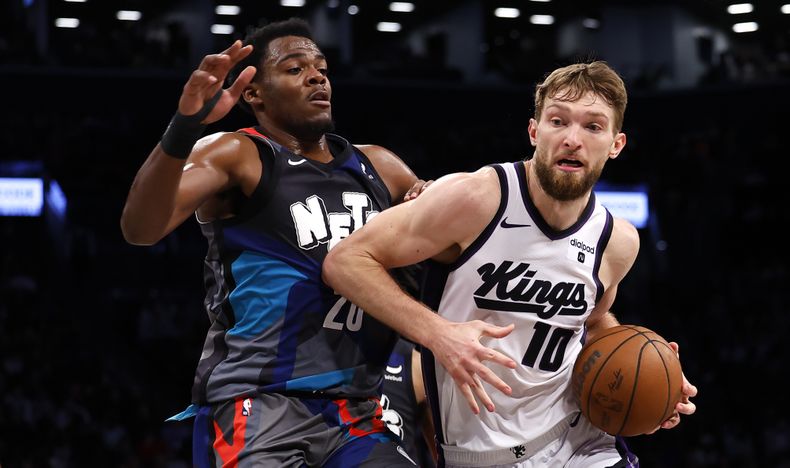 El alero de los Kings de Sacramento, Domantas Sabonis (10), conduce hacia la canasta contra el pívot de los Nets de Brooklyn DayRon Sharpe (20) durante la segunda mitad de un partido de baloncesto de la NBA, el domingo 7 de abril de 2024, en Nueva York. Los Kings ganaron 107-77. (AP Foto/Noah K. Murray)