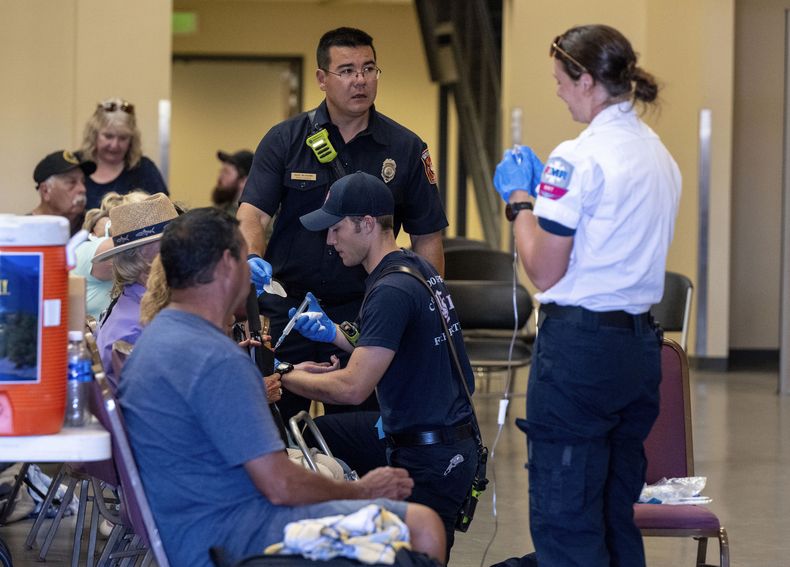 Bomberos y paramédicos atienden a personas afectadas por el calor durante un espectáculo aéreo el sábado 17 de agosto de 2024 en Colorado Springs, Colorado. (Parker Seibold/The Gazette vía AP)