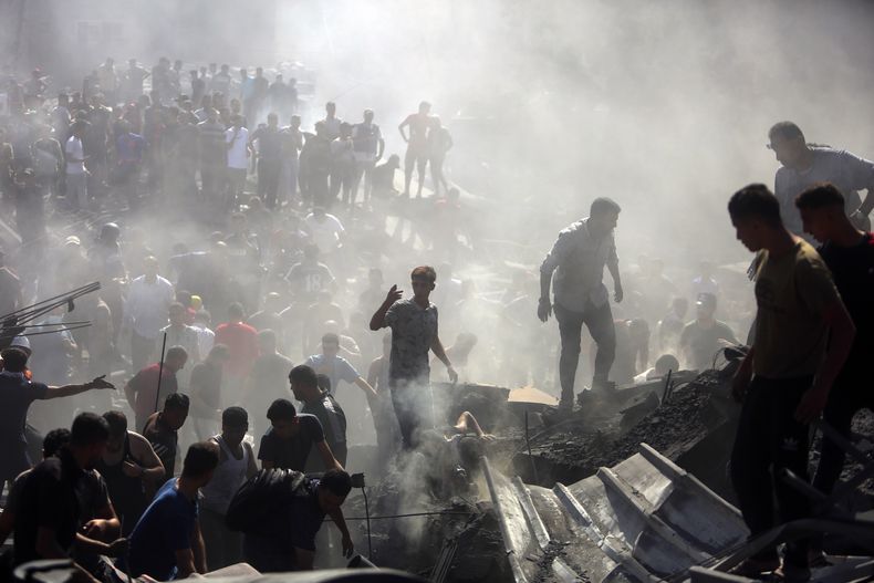 Palestinos inspeccionan los restos de edificios destruidos tras ataques aéreos israelíes sobre la ciudad de Khan Younis, en el sur de la Franja de Gaza, el 26 de octubre de 2023. (AP Foto/Mohammed Dahman)