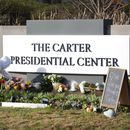 Christine Mason, de Atlanta, coloca flores a la entrada del Centro Presidencial Jimmy Carter el lunes 30 de diciembre de 2024, en Atlanta. El expresidente Carter falleció el domingo en su casa en Plains, Georgia, a la edad de 100 años. (AP Foto/John Bazemore)