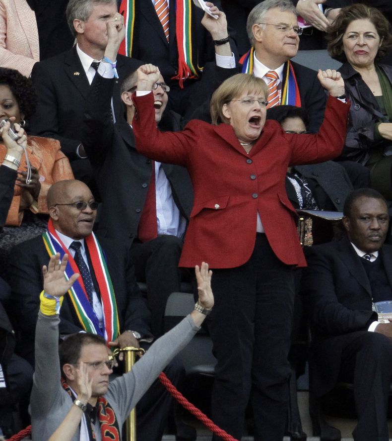 En esta foto del 3 de julio de 2010, la Canciller alemana Angela Merkel salta junto al presidente sudafricano Jacob Zuma, durante un partido de cuartos de final entre la selecci&oacute;n de su pa&iacute;s y Argentina, en Ciudad del Cabo (AP Foto/Gero Brel