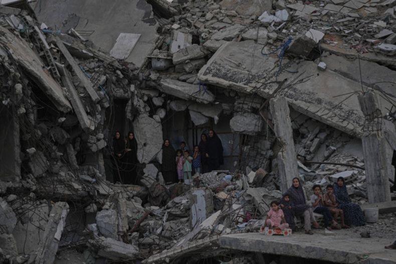 Mujeres y niños palestinos ven el torneo de fuerza Palestine Strongman Championship entre los escombros de edificios destruidos en Ciudad de Gaza, el viernes 16 de octubre de 2026. (AP Foto/Jehad Alshrafi)