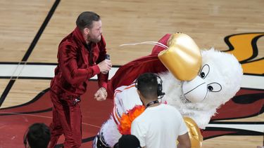 El excombatiente de artes marciales mixtas Conor McGregor propina un puñetazo a Burnie, mascota del Heat de Miami, durante una pausa en el cuarto partido de las Finales de la NBA ante los Nuggets de Denver, el viernes 9 de junio de 2023 (AP Foto/Lynne Sladky)