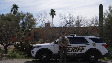 Un miembro de la policía del condado Pima se ve junto a su vehículo ante la casa de Nancy Guthrie el martes 10 de febrero de 2026 en Tucson, Arizona. (AP Foto/Ty ONeil)