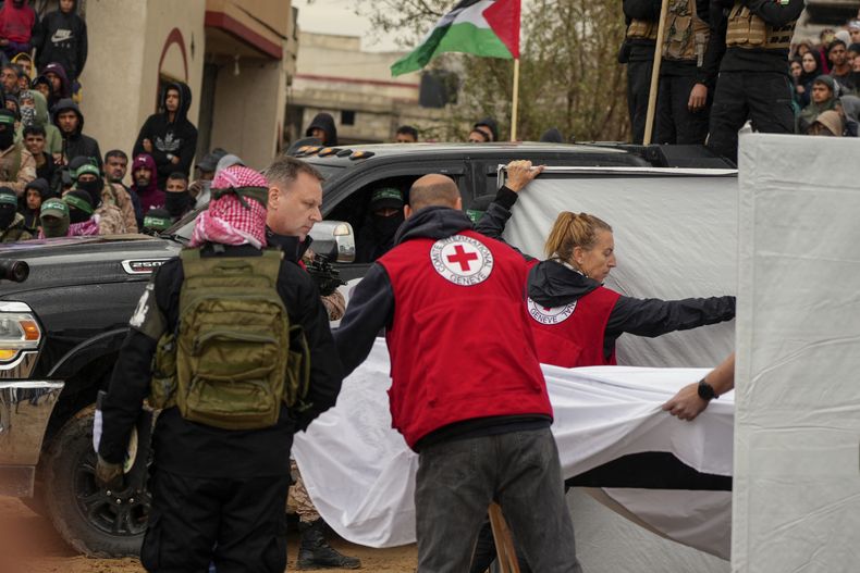 Combatientes de Hamás entregan un féretro que contiene uno de los cuatro cadáveres de rehenes israelíes, incluyendo una madre y sus dos hijos a personal de la Cruz Roja en Jan Yunis, en el sur de la Franja de Gaza, el jueves 20 de febrero de 2025. (AP Foto/Abdel Kareem Hana)