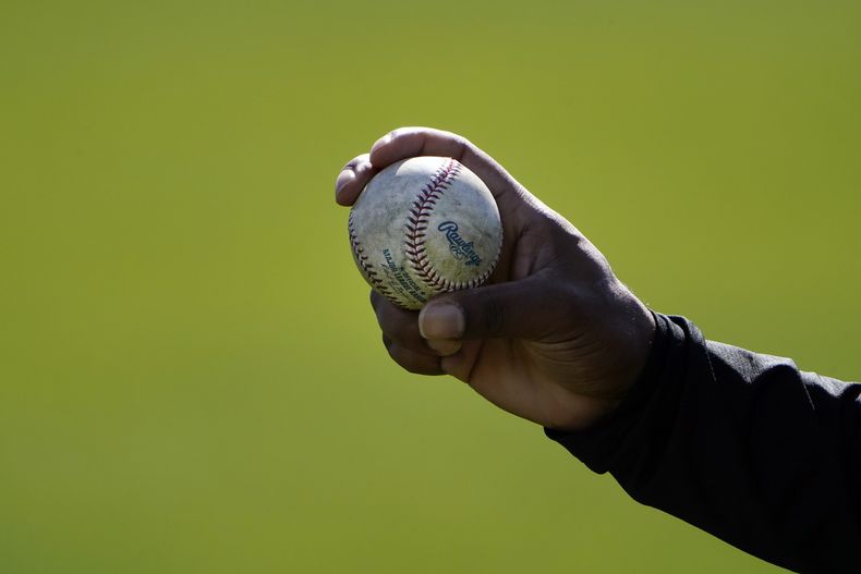 Un lanzador de los Rockies de Colorado muestra cómo sujeta la pelota durante un entrenamiento de pretemporada en Scottsdale, Arizona, el 24 de febrero de 2021 (AP Foto/Jae C. Hong)