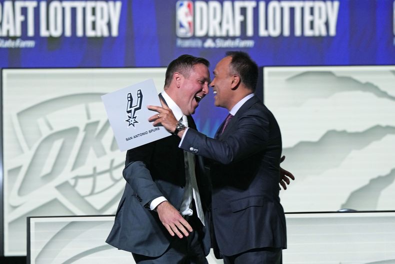 Peter J. Holt, socio administrativo de los Spurs de San Antonio, abraza al subcomisionado de la NBA, Mark Tatum, luego que el equipo ganó la lotería del draft en Chicago, el martes 16 de mayo de 2023 (AP Foto/Nam Y. Huh)