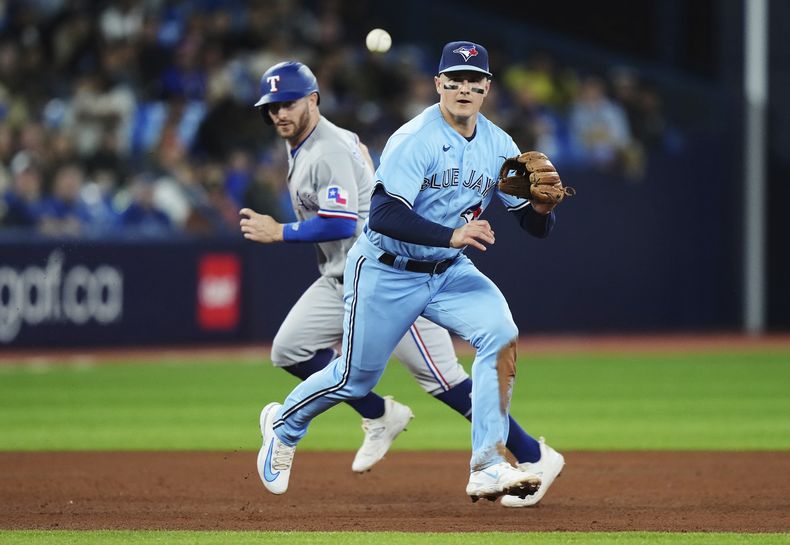 ARCHIVO - El tercera base de los Azulejos de Toronto Matt Chapman se prepara para atrapar un contacto del dominicano Ezequiel Durán de los Texas Rangers, mientras que Robbie Grossman corre hacia tercera durante la 5ta entrada del juego de béisbol en Toronto, el jueves 14 de septiembre de 2023. (Nathan Denette/The Canadian Press via AP, File)