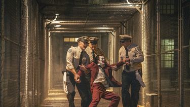 Esta imagen proporcionada por Warner Bros. Pictures muestra a Joaquin Phoenix, en primer plano al centro, y Brendan Gleeson, al fondo en el centro, en una escena de Joker: Folie à Deux. (Niko Tavernise/Warner Bros. Pictures vía AP)