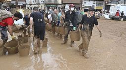 Voluntarios cargan cubetas con lodo tras las inundaciones en Paiporta, cerca de Valencia, España, el 3 de noviembre de 2024. (AP Foto/Hugo Torres)