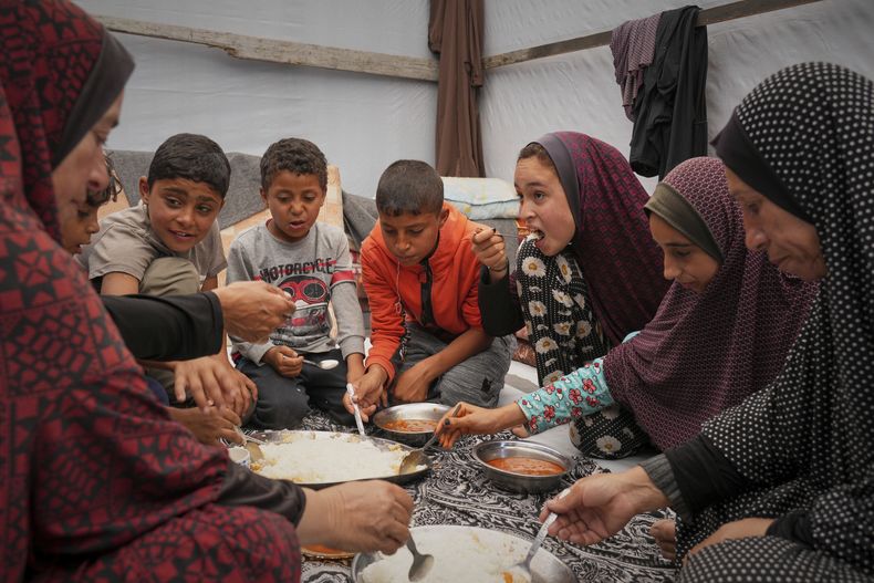 La familia Al-Najjar comiendo guisantes y arroz en una tienda de campaña en Muwasi, en las afueras de Jan Yunis en la Franja de Gaza, el 25 de abril del 2025. (AP foto/Abdel Kareem Hana)