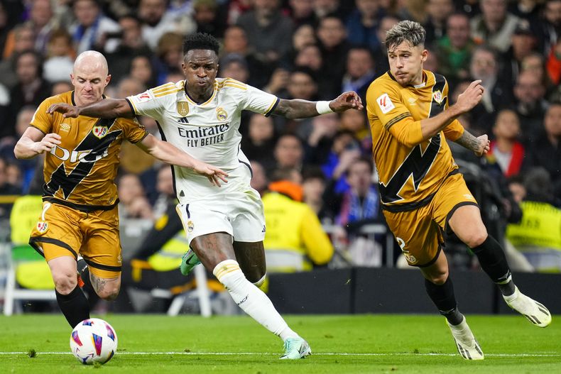 Vinicius Junior del Real Madrid pelea por el balón con Isi Palazon y Andrei Ratiu del Rayo Vallecano en el encuentro de la liga española el domingo 5 de noviembre del 2023. (AP Foto/Manu Fernandez)