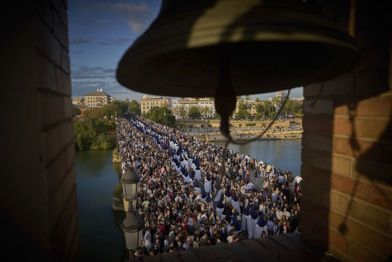 Penitentes de la hermandad de la Estrella participan en una procesión de Semana Santa que cruza el llamado puente de Triana, en Sevilla, España, el 13 de abril de 2025. (AP Foto/Emilio Morenatti)