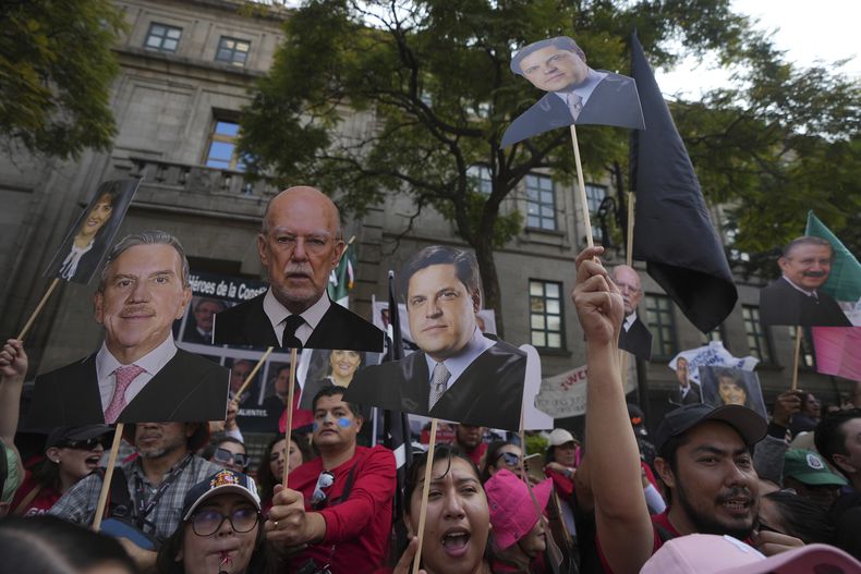 Empleados del Ministerio Público sostienen imágenes de los magistrados de la Suprema Corte en señal de apoyo mientras discuten un proyecto de resolución que propone la invalidación parcial de la reforma judicial aprobada por el Congreso, en la Ciudad de México, el martes 5 de noviembre de 2024. (Foto AP/Fernando Llano)