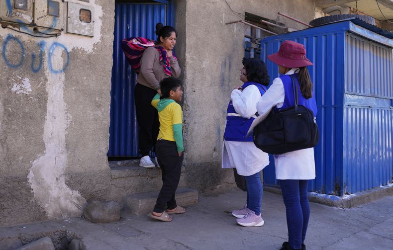 Trabajadores de salud hablan con residentes puerta a puerta en una campaña de vacunación contra el sarampión en La Paz, Bolivia, el martes 1 de julio de 2025. (AP Foto/Juan Karita)