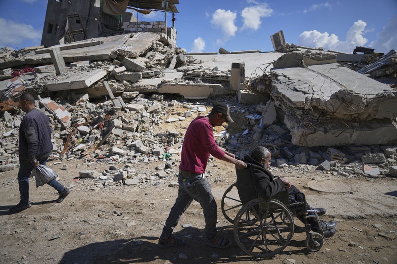 ARCHIVO - Wasem Attiya empuja la silla de ruedas de su padre, Mohamed, de 54años, mientras se dirigen al Hospital Shifa de la Ciudad de Gaza para una sesión de diálisis, el lunes 14 de abril de 2025. (AP Foto/Jehad Alshrafi, Archivo)