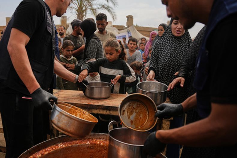 Palestinos reciben alimentos donados por el Programa Mundial de Alimentos en un campamento de desplazados, el domingo 18 de octubre de 2026, en Deir al-Balah, en el centro de la Franja de Gaza. (AP Foto/Abdel Kareem Hana)
