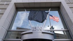 La bandera estadounidense junto a una asta vacía que sostenía la bandera de la Agencia de los Estados Unidos para el Desarrollo Internacional (USAID, por sus siglas en inglés), se refleja en una ventana que mostraba el nombre y el sello de la USAID, fuera de las oficinas de la agencia en Washington, el viernes 7 de febrero de 2025. (AP Foto/Jose Luis Magana)