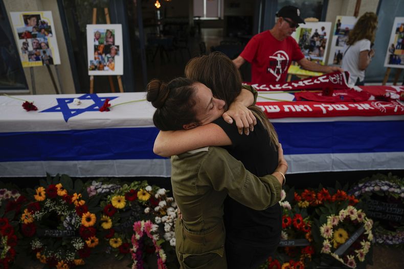 Dos personas se abrazan durante el funeral por Meni y Ayelet Godard, en el kibutz de Palmachim, Israel, el 29 de octubre de 2023. (AP Foto/Ariel Schalit)