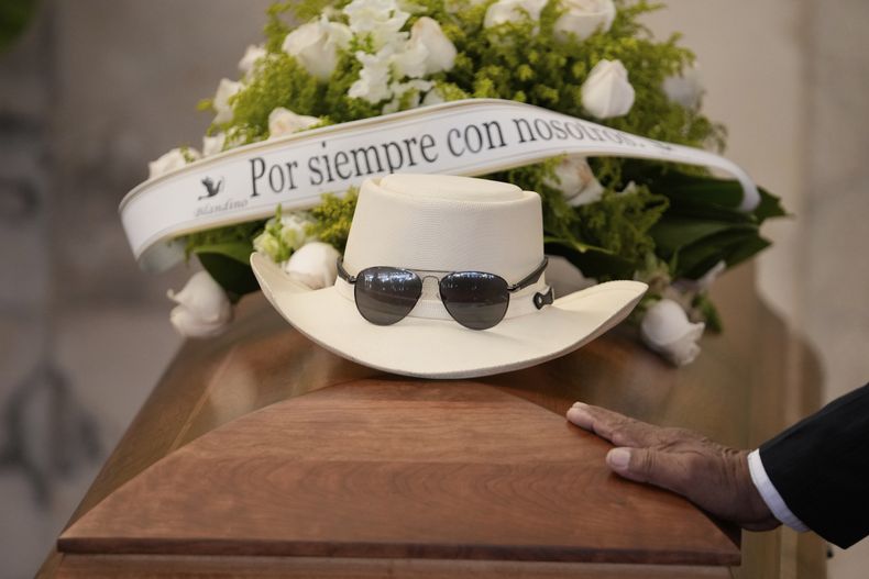 El sombrero y las gafas de sol del cantante dominicano Rubby Perez, fallecido en el derrumbe del techo del club nocturno Jet Set mientras daba un concierto de merengue, sobre su ataúd durante su velorio en el Teatro Nacional Eduardo Brito en Santo Domingo, República Dominicana, el jueves 10 de abril de 2025. (AP Foto/Matias Delacroix)