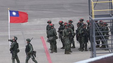 En esta imagen de archivo, un soldado taiwanés sostiene una bandera de Taiwán cerca de un grupo de soldados con marcas rojas en sus cascos porque se harán pasar por enemigos durante las maniobras anuales Han Kuang, que simulan un ataque a un aeródromo, en el aeropuerto internacional Taoyuan, en Taoyuan, Taiwán, el 26 de julio de 2023. (AP Foto/Chiang Ying-ying, archivo)