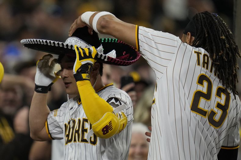 El jugador de los Padres de San Diego Fernando Tatis Jr. (23) pone un sombrero a su compañero Ha-Seong Kim después de que Kim pegara un jonrón de tres carreras en el quinto inning de su juego de béisbol contra los Rojos de Cincinnati, el lunes 1 de mayo de 2023 en San Diego. (AP Foto/Gregory Bull)