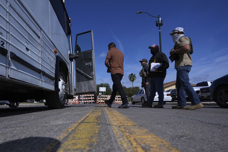 Agentes federales escoltan a un hombre a un autobús después de que fue detenido tras presentarse en un tribunal migratorio, el martes 22 de julio de 2025, en San Antonio. (AP Foto/Eric Gay)
