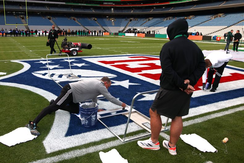 Trabajadores ponen los últimos detalles del logo de la NFL para el juego de los Vikings de Minnesota ante Steelers de Pittsburgh en Dulbín el domingo 28 de septiembre del 2025. (AP Foto/Ian Walton)