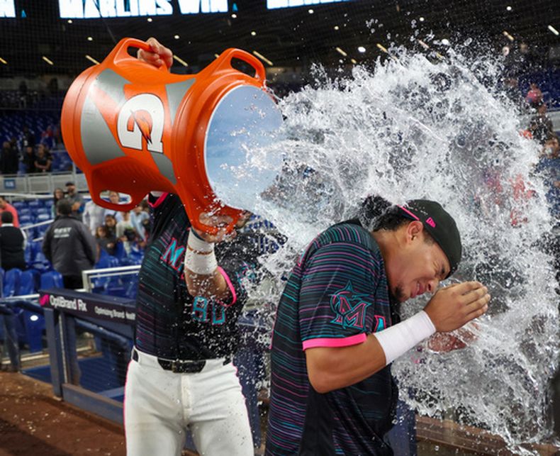 El venezolano Javier Sanoja es empapado con la hielera por Joe Mack, su compañero de los Marlins de Miami, tras conectar el hit del triunfo sobre los Nacionales de Washington, el viernes 21 de agosto de 2026 (AP Foto/David Santiago)
