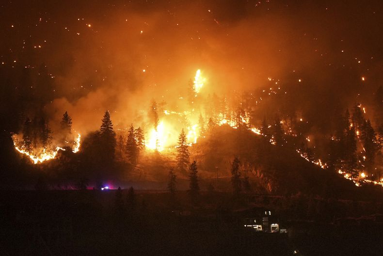 El incendio de McDougall Creek arde en las montañas sobre una vivienda a orillas de un lago en West Kelowna, Canadá, el 18 de agosto de 2023. (Darryl Dyck/The Canadian Press vía AP)
