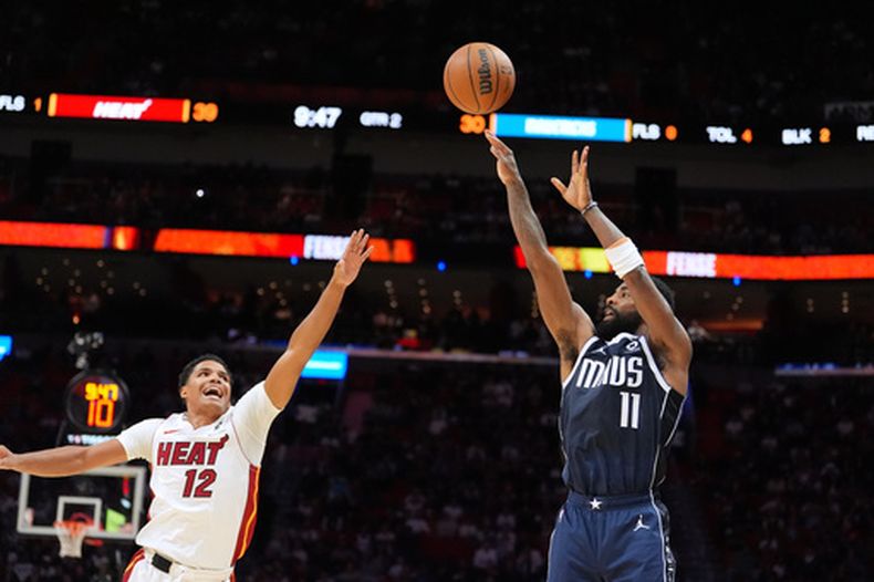 El base de los Mavericks de Dallas Kyrie Irving lanza el balón sobre el base del Heat de Miami Dru Smith en el encuentro del lunes 26 de octubre del 2026. (AP Foto/Rebecca Blackwell)