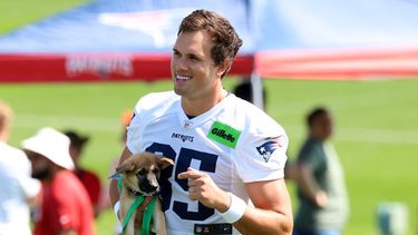 El ala cerrada de los Patriots de Nueva Inglaterra, Hunter Henry, camina con un perro, parte del programa de adopción de perros del equipo en el primer día del campamento de entrenamiento de fútbol americano, el sábado 25 de julio de 2026, en Foxborough, Massachusetts. (Foto AP/Mark Stockwell)