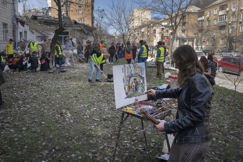 Una alumna de la Academia Estatal de Arte de Kiev pinta mientras otros alumnos y voluntarios despejan los escombros tras la destrucción parcial de la Academia en un ataque de misiles ruso unos días antes, en Kiev, Ucrania, el sábado 30 de marzo de 2024. (AP Foto/Efrem Lukatsky)