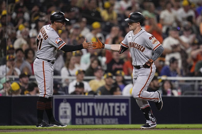 Mike Yastrzemski, de los Gigantes de San Francisco, festeja con Mark Hallberg, el coach de la antesala, luego de batear un jonrón en el duelo del jueves 31 de agosto de 2023, ante los Padres de San Diego (AP Foto/Gregory Bull)