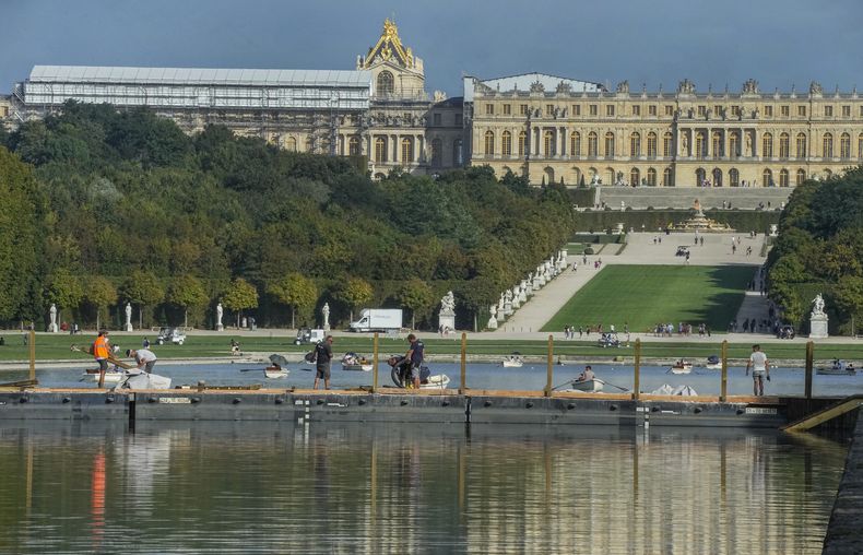 Trabajadores de construcción se paran en un puente que atraviesa el Gran Canal del Palacio de Versalles, el martes 22 de agosto de 2023 (AP Foto/Michel Euler)