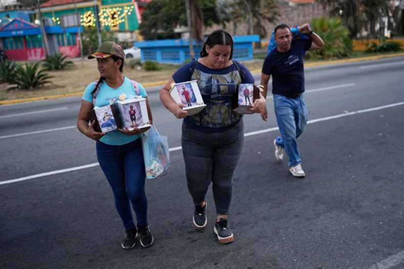 Eucaris Silva (izquierda) y Leida Suárez (centro) sostienen las urnas con las cenizas de los miembros de su familia que fallecieron en los terremotos de La Guaira, Venezuela, el sábado 15 de agosto de 2026. (Foto AP/Ariana Cubillos)