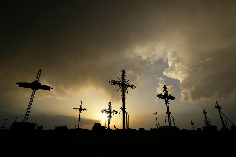 En esta imagen de archivo, la silueta de cruces de hierro que indican la presencia de tumbas, recortadas contra un cielo de tormenta en un cementerio, el 25 de mayo de 2024, en Victoria, Kansas. (AP Foto/Charlie Riedel, archivo)