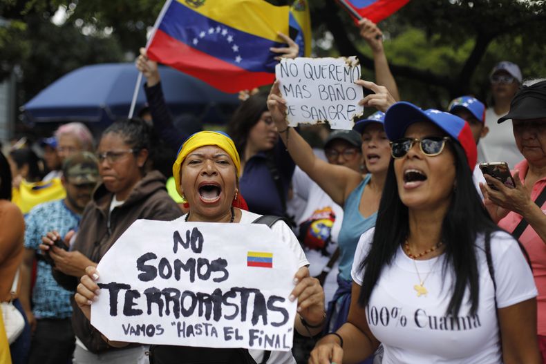 Una mujer sostiene un cartel con un mensaje que dice No somos terroristas. Vamos hasta el final, mientras espera junto a sus compañeros partidarios la llegada de la líder opositora María Corina Machado, en Caracas, Venezuela, el sábado 3 de agosto de 2024. (Foto AP/Cristian Hernández)
