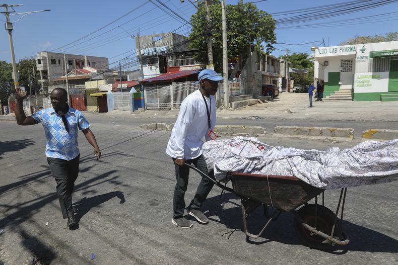 Unos hombres transportan el cuerpo de un hombre que murió durante un ataque de pandillas en el vecindario de Delmas, en Puerto Príncipe, Haití, el martes 25 de febrero de 2025. (AP Foto/Odelyn Joseph)