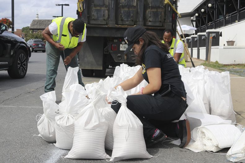 Nicole Torres, portavoz de la Oficina de Gestión de Emergencias de la ciudad de Annapolis, Maryland, ata sacos de arena, el viernes 22 de septiembre de 2022, mientras residentes se preparan para la llegada de una tormenta. (AP Foto/Brian Witte)