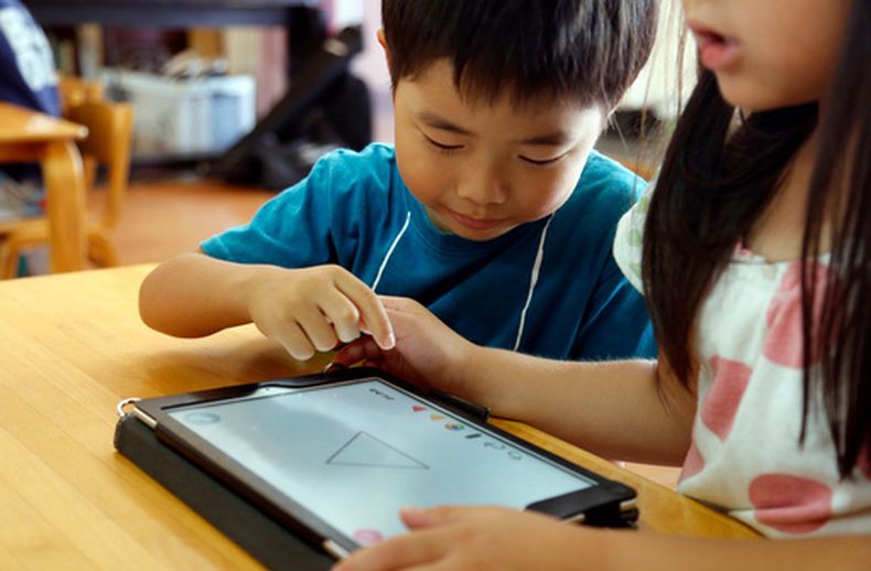 Niños usan dispositivos digitales en una escuela en Yoshikawa, un suburbio de Tokio, el 12 de julio del 2018. (AP foto/Yuri Kageyama)