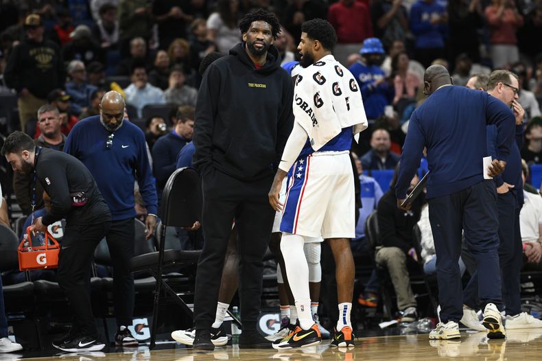 ARCHIVO - Joel Embiid, centro izquierda, pívot de los Sixers de Filadelfia, habla con el alero Paul George durante un tiempo muerto en la segunda mitad del juego de baloncesto de la NBA en contra del Magic de Orlando, el domingo 12 de enero de 2025, en Orlando, Florida. (AP Foto/Phelan M. Ebenhack, Archivo)