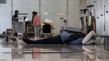 Una persona duerme en el piso de la terminal 4 del aeropuerto Adolfo Suárez-Madrid Barajas en Madrid, España, el 12 de mayo de 2025. (Diego Radames/Europa Press via AP)