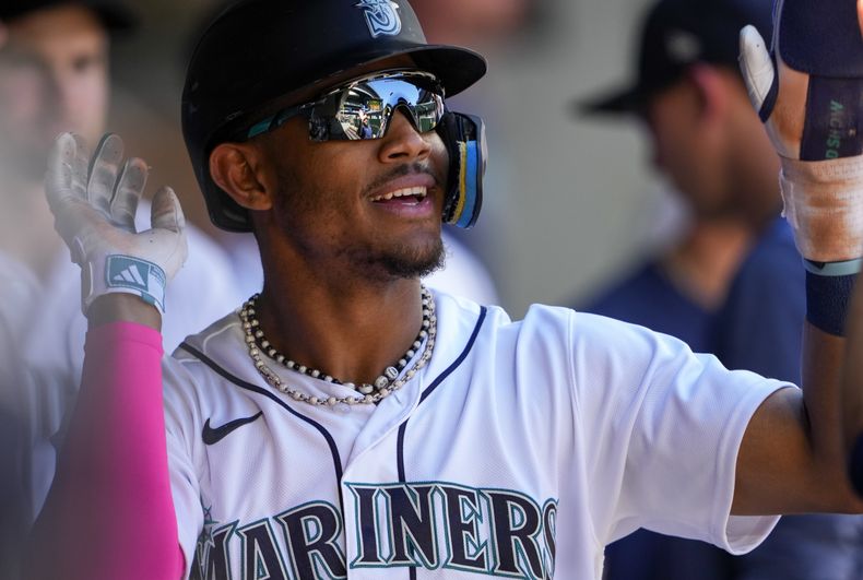 El dominicano Julio Rodríguez, de los Marineros de Seattle, festeja en la cueva luego de robarse el plato en el juego del miércoles 2 de agosto de 2023, ante los Medias Rojas de Boston (AP Foto/Lindsey Wasson)
