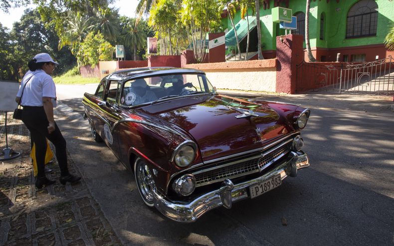 Una oficial de carrera controla un automóvil durante el Rally de Autos Antiguos de La Habana, en La Habana, Cuba, el domingo 3 de diciembre de 2023. El rally celebra el 125to aniversario de la llegada del primer automóvil a la isla. (Foto AP/Ismael Francisco)