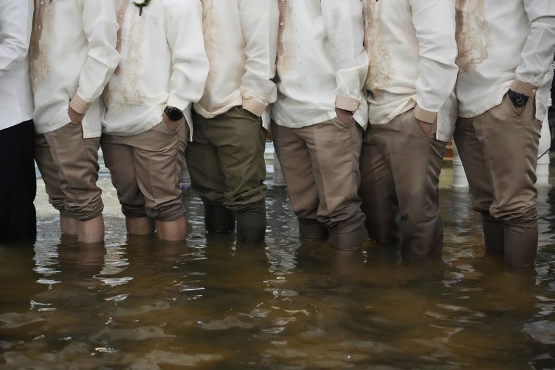 Invitados de una boda de pie en la iglesia inundada de Barasoain, en Malolos, capital de la provincia de Bulacán, Filipinas, el martes 22 de julio de 2025. (AP Foto/Aaron Favila)