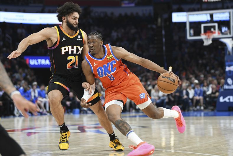 Jalen Williams, alero del Thunder de Oklahoma City, elude a David Roddy, de los Suns de Phoenix, en el encuentro del viernes 29 de marzo de 2024 (AP Foto/Kyle Phillips)