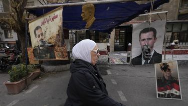 Zapatos colgados frente a retratos del depuesto presidente sirio Bashar Assad en Damasco, Siria, lunes 23 de diciembre de 2024. (AP foto/Hussein Malla)